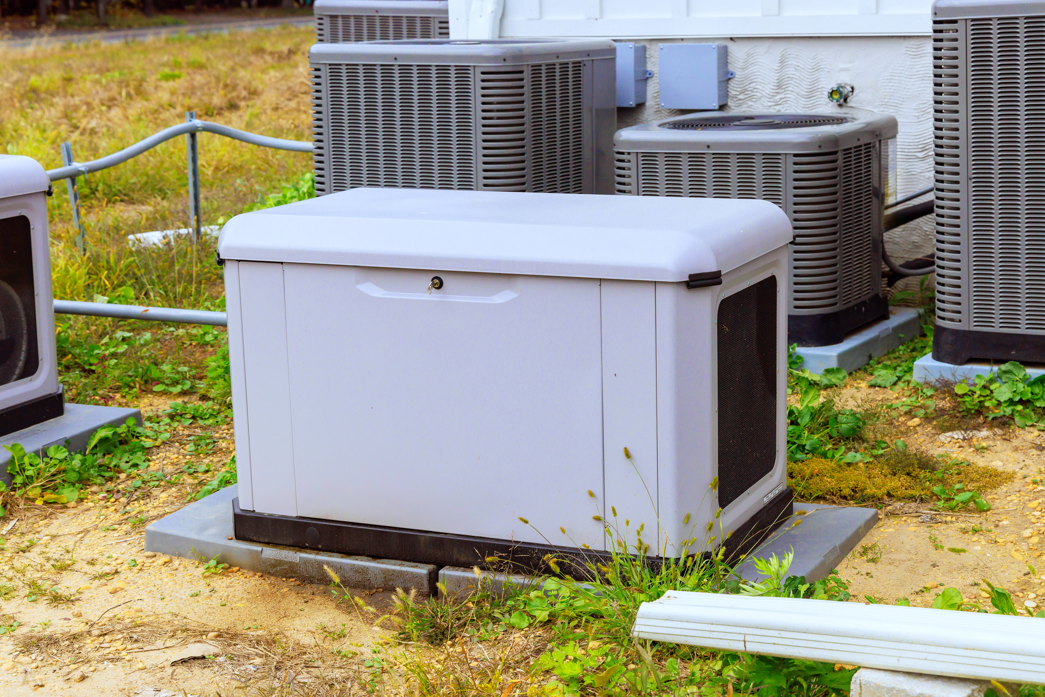 Generator in a backyard with HVAC units in the background