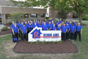 Robin Aire team members dressed in blue uniforms standing behind Robin Aire business signage.