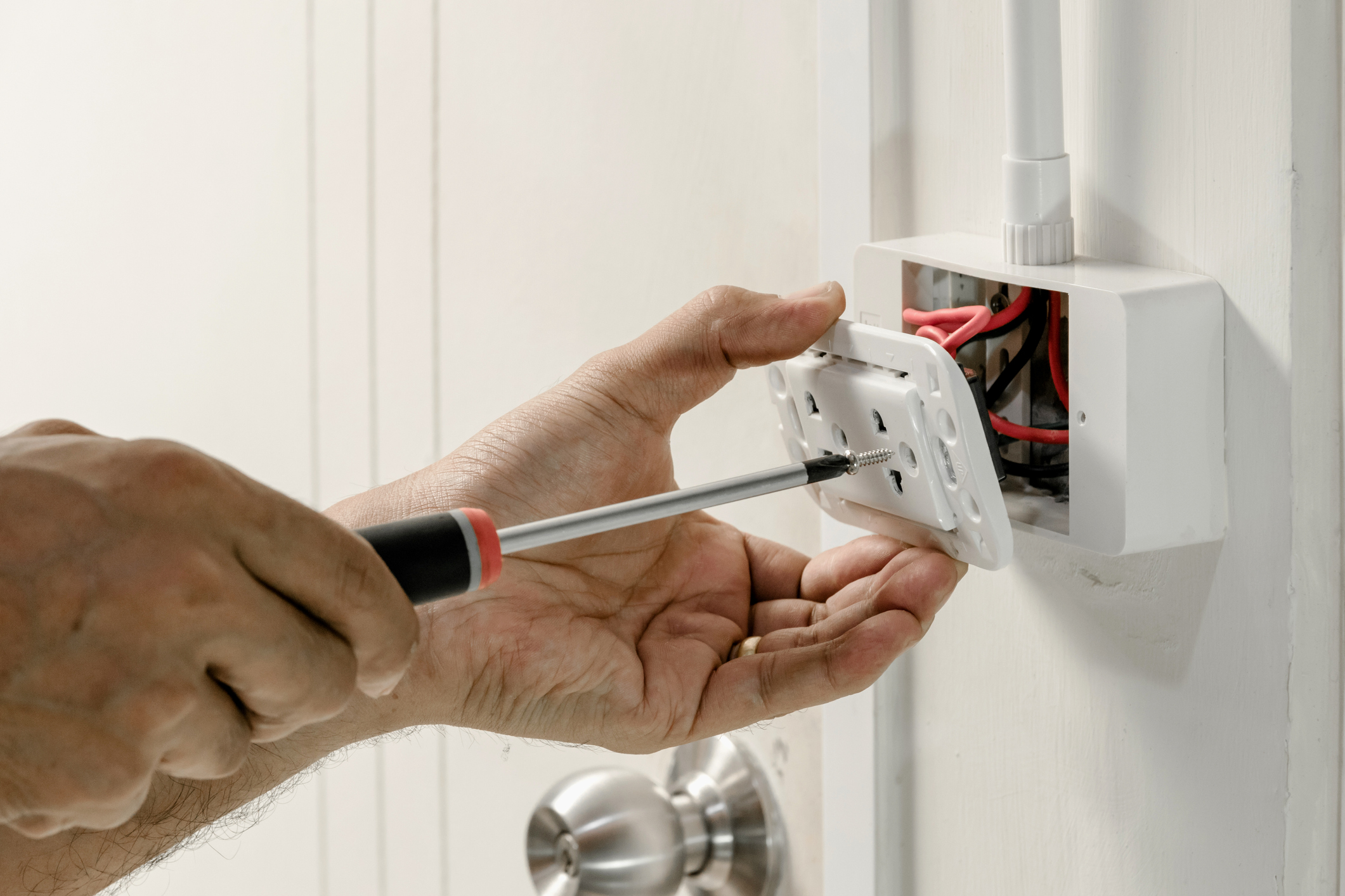 Electrician's hand using a screwdriver to fix an outlet