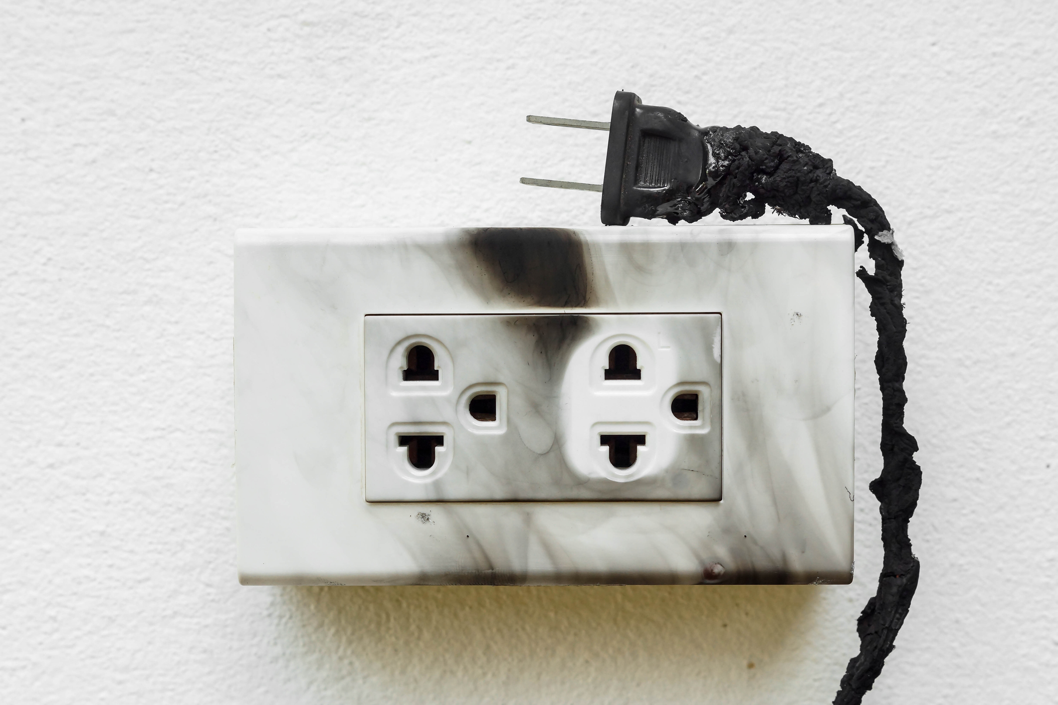 Scorched outlet with a burnt & melted cord resting on it