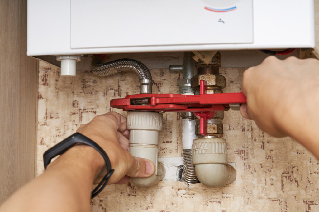 Plumber repairing gas water heater in home